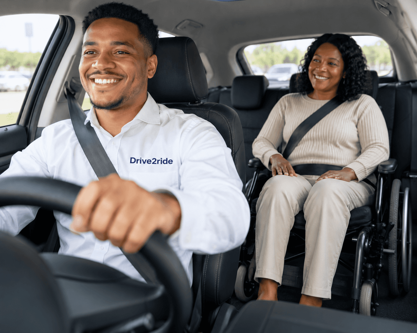 A Drive2Ride driver and passenger smiling inside the vehicle